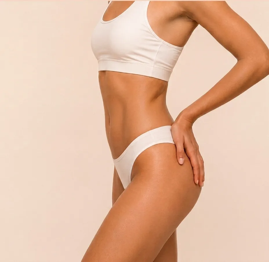 Torso de perfil de una mujer en ropa deportiva clara, con la mano apoyada en la cadera.