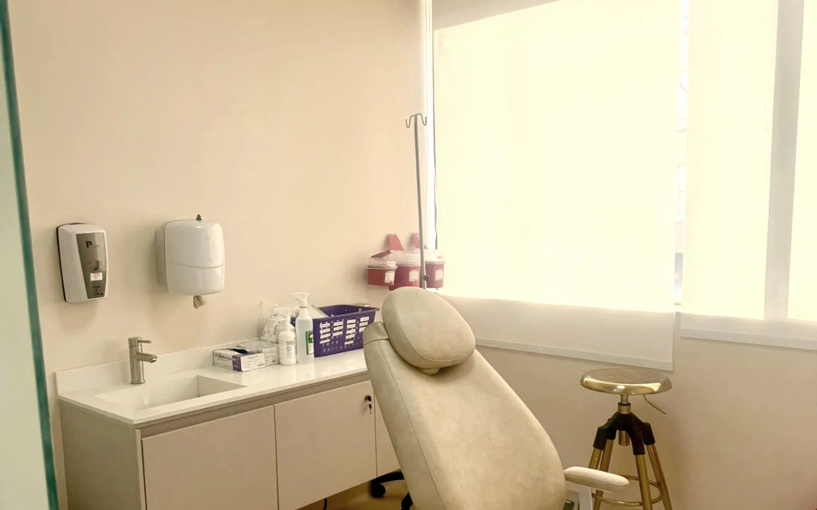Sala de procedimientos vacía de la sede de Reviá en Bogotá, con camilla reclinable, lavamanos y luz natural filtrada por una persiana.